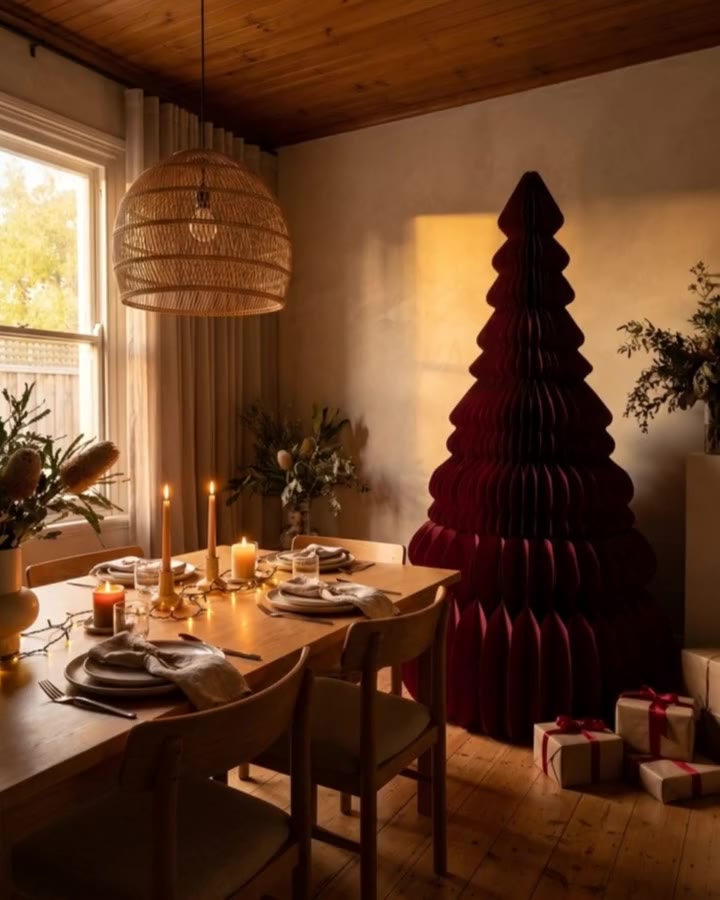 A burgundy Élan paper Christmas tree in a candlelit dining room